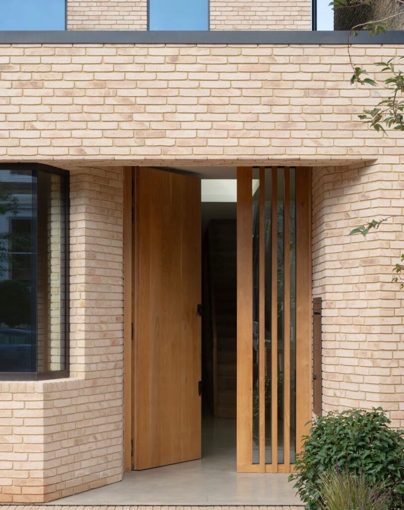 Contemporary entrance detail with bespoke timber door and curved brickwork within a residential extension project