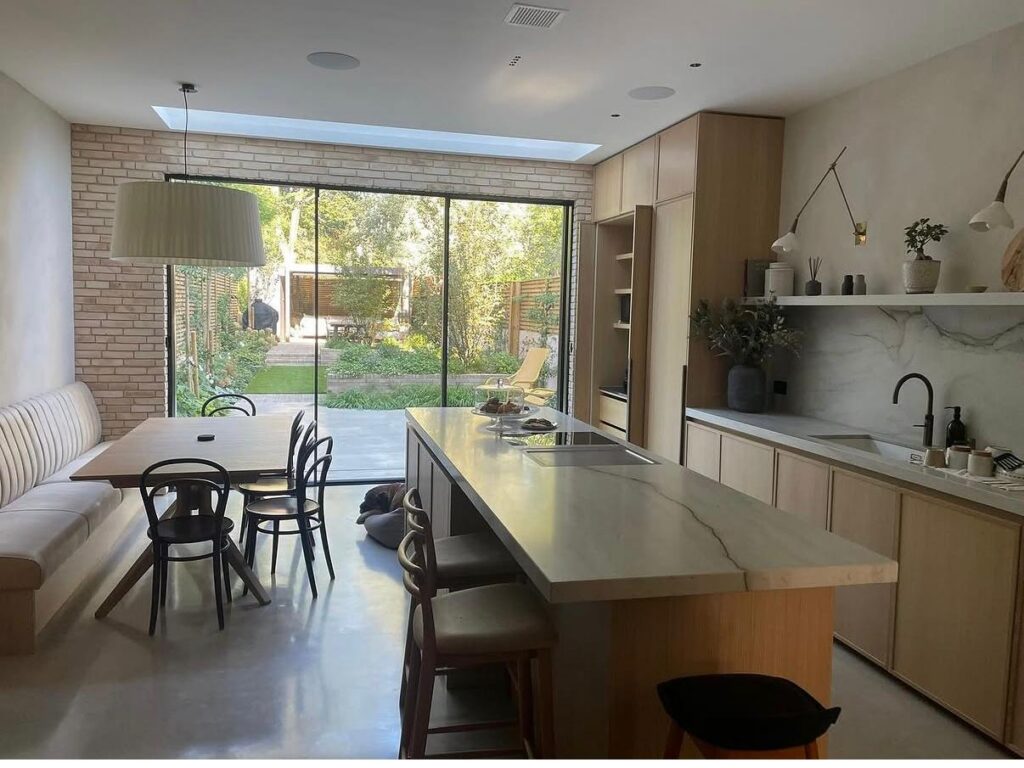 Open-plan kitchen and dining space featuring bespoke cabinetry, large-format glazing and direct garden connections